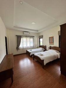 a large room with two beds and a table at The deer resort in Chiang Mai