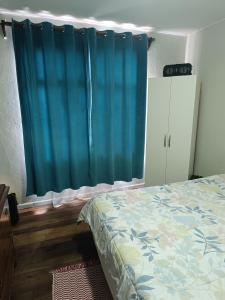 1 dormitorio con cama y cortina azul en Habitación grande céntrica, en La Serena