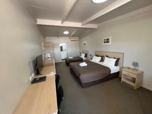 ein Schlafzimmer mit einem Bett, einem Sofa und einem TV in der Unterkunft Highway One Motel in Ceduna