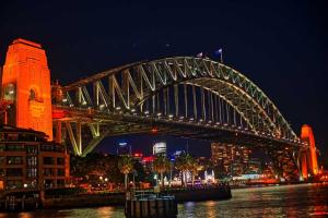 a large bridge over the water at night at Space Q Capsule Hotel in Sydney