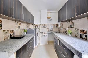 a large kitchen with gray cabinets and marble counter tops at Flagship Khanpur STAY in New Delhi