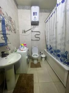 een badkamer met een wastafel, een toilet en een bad bij Center Cozy Apartment in Bisjkek