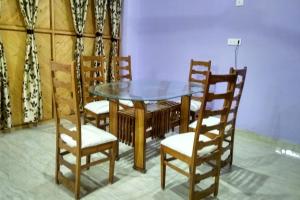 uma mesa de jantar e cadeiras com uma tampa de vidro em Collection O Shivanya Guest House em Kakarmatha