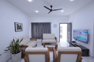 een woonkamer met een bank en een tv bij INDIGO PALMS in Trivandrum
