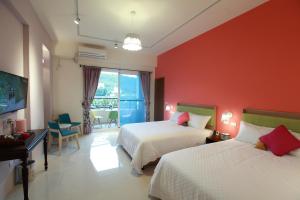 a bedroom with two beds and a red wall at 坡岸長堤民宿 Leveeside House in Hualien City