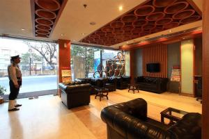 コルカタにあるホテル O2 VIPの革製家具を備えた部屋に立つ男