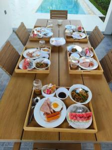 una mesa con varios platos de comida. en 可提供早餐的三卧私家泳池家庭别墅 en Ban Huai Yai