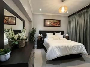 a bedroom with a large bed with white sheets at Kiwi Boutique Lodges in Pretoria