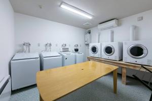 eine Waschküche mit weißen Geräten und einem Holztisch in der Unterkunft THE NORTH PEAK 104 in Furano