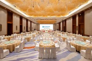 a large banquet hall with tables and white chairs at Wyndham Nankunshan in Cenkeng