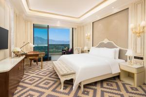 a bedroom with a large white bed and a desk and a piano at Wyndham Nankunshan in Cenkeng