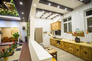 eine große Küche mit Holzschränken und weißen Fliesen in der Unterkunft Tengchong Old Town Peace Inn in Tengchong