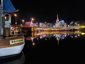 een boot in het water met een stad in de nacht bij Hanza Tower Sky Pool & Jacuzzi & Sauna in Szczecin