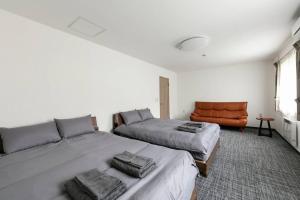 1 Schlafzimmer mit 2 Betten und einem orangenen Stuhl in der Unterkunft THE NORTH PEAK 201 in Furano