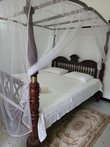 Schlafzimmer mit Himmelbett und weißer Bettwäsche in der Unterkunft Villa sea spray in Hikkaduwa