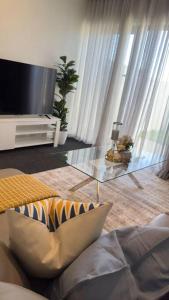 a living room with a tv and a glass table at Stylish modern 2 BR in Lawson in Belconnen