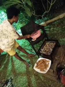 a man standing next to a grill with a plate of food at elephant eye safari house in Udawalawe