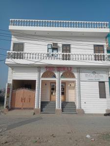 a large white building with a porch and stairs at OYO Hotel The Miraj in Sonīpat