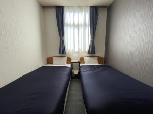 two beds in a small room with a window at Zentsuji Grand Hotel in Zentsuji