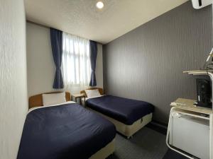 a hotel room with two beds and a television at Zentsuji Grand Hotel in Zentsuji