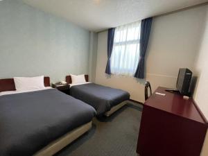 a hotel room with two beds and a television at Zentsuji Grand Hotel in Zentsuji