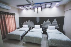 een kamer met drie bedden en een zwart-witte muur bij Hotel RoseWood in Karachi