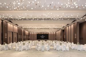 a ballroom with white tables and chairs and a screen at Crowne Plaza Jinan Runhua in Jinan