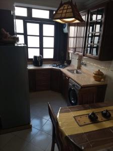 a kitchen with a sink and a refrigerator and a table at Appt, Agréable Lumineux et ensoleillé in Agadir