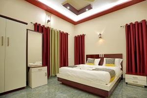 a bedroom with a bed with red curtains and a mirror at Loreal Luxury Holiday villa in Ambalavayal