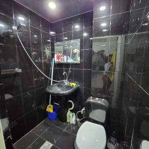 uma casa de banho com azulejos pretos, um WC e um lavatório. em Pet-Friendly Home with Yard em Yerevan