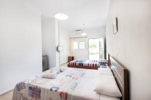 a white bedroom with two beds and a mirror at Istira in Possidi