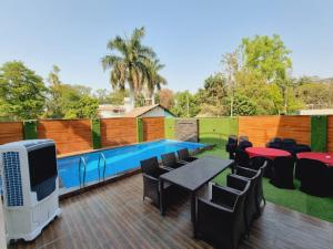 a swimming pool with a table and chairs and a television at Ishara villa in Indore