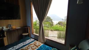 Schlafzimmer mit einem Fenster mit Blick auf ein Feld in der Unterkunft Sky View Bromo Guest House in Ngadisari