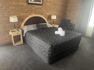a bedroom with a bed and two tables with lamps at Charles sturt motor inn in Cobram