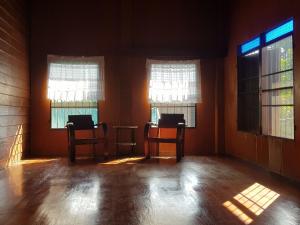 an empty room with two chairs and two windows at Kedthawa Homestay เฮือนเก็ดถะหวา in Ban Cho Lae