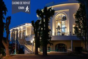 Un grand bâtiment blanc avec des escaliers se trouve juste devant. dans l'établissement Le Royat Palace - Wifi - Confort, à Royat
