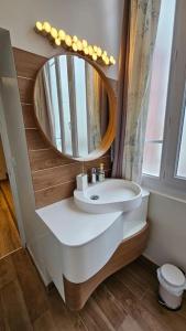 La salle de bains est pourvue d'un lavabo et d'un miroir. dans l'établissement Le Royat Palace - Wifi - Confort, à Royat