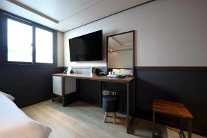 a bedroom with a desk with a tv and a mirror at Hotel Mar Samsan in Ulsan