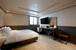 a bedroom with a bed and a desk with a television at Hotel Mar Samsan in Ulsan