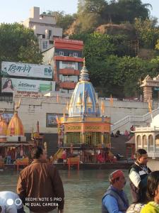 a group of people standing around a temple in the water at Hotel Aarti Darshan in Haridwār