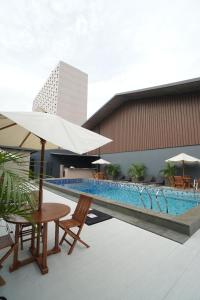 a swimming pool with a table and chairs and an umbrella at Sentral Cawang Hotel in Jakarta