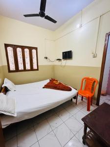 una camera con letto e sedia arancione di Satsang Lodge a Varanasi