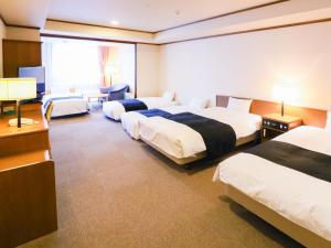 a hotel room with three beds and a television at APA Hotel Sapporo Susukino Ekinishi in Sapporo