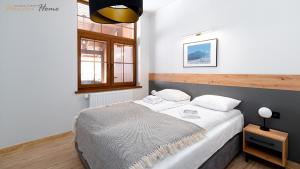 a bedroom with a large bed with white sheets at Wonder Home - Apartamenty Karkonosz blisko wyciągów narciarskich, szlaków i restauracji in Karpacz +71 photos
