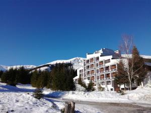 un bâtiment dans la neige devant une montagne dans l'établissement Hotel SOREA MARMOT, à Demänovská Dolina