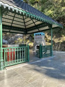 a pavilion with a fireplace and a green fence at Carabean Villa in Dalhousie