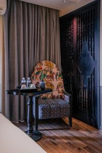 einen Stuhl mit einem Tisch in einem Zimmer mit einem Vorhang in der Unterkunft Hanoi Center Silk Classic Hotel & Travel in Hanoi