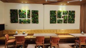 una sala da pranzo con tavoli, sedie e dipinti alle pareti di 車站100m民宿丨電梯附停車場 a Città di Hualien