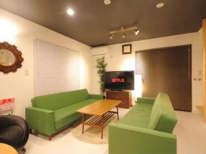 a living room with a green couch and a table at Fuji Time traveler 新館 in Fujikawaguchiko