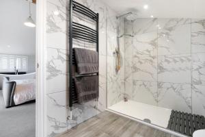 a bathroom with a walk in shower and a tub at Priory Farm Cottage in Colchester